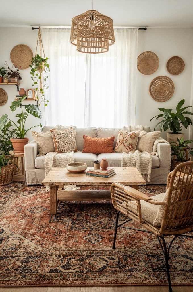 Vintage Persian rug anchoring a cozy seating area with neutral sofa, woven pendant light and rattan furniture in a boho living room.