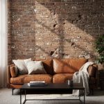 Industrial living room with exposed brick wall, leather sofa, and metal accents creating a warm and balanced interior.