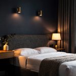 Moody boutique bedroom with upholstered headboard, warm bedside lighting, and asymmetrical nightstands in a dark, cozy setting.