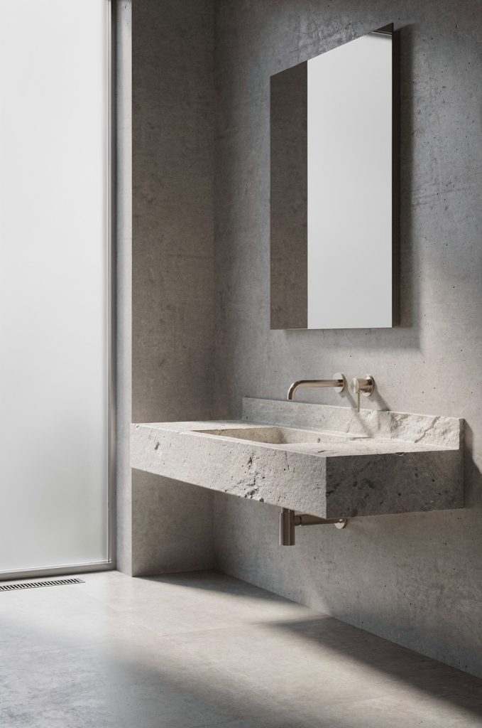 Minimal industrial bathroom with wall-mounted stone sink, exposed plumbing, concrete wall, and simple mirror.