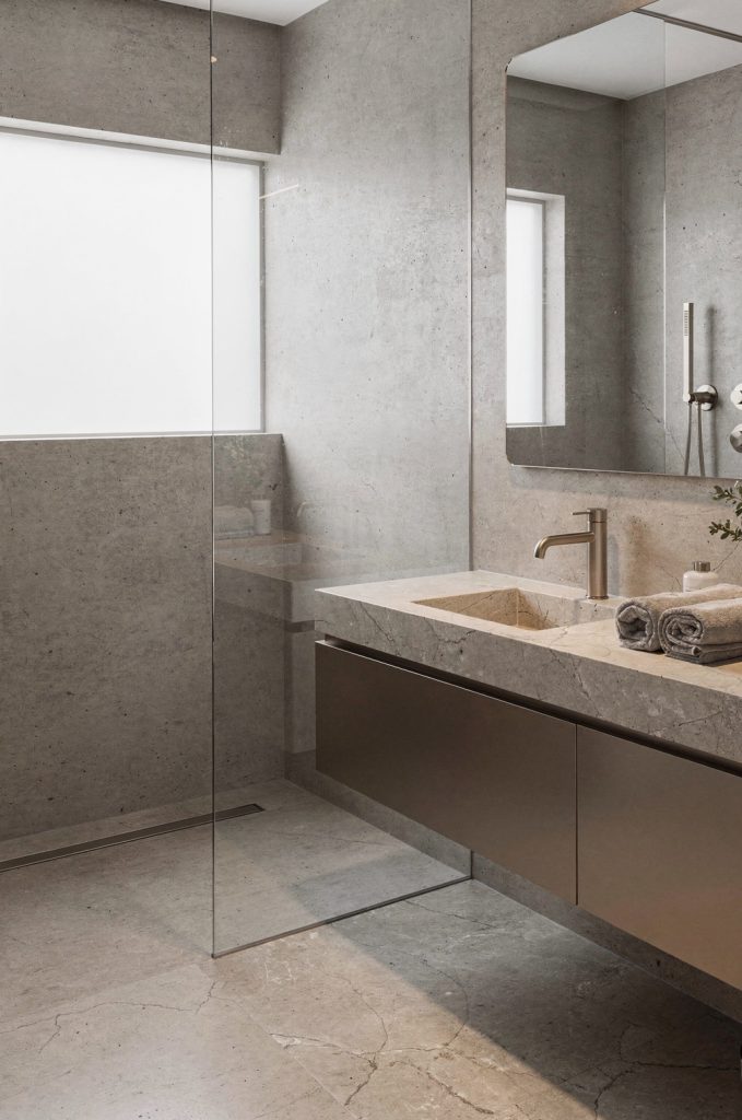 Modern industrial bathroom with wall-mounted vanity, concealed drawers, integrated sink, and concrete wall finish.